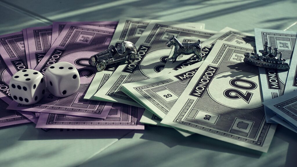 Close-up of Monopoly game components including dice and miniature pieces on colorful cash.